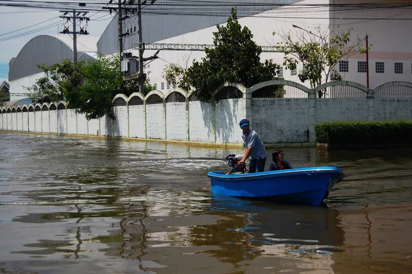 Thai people natural disaster victims use vessel wading in water on street of alley while water flood road wait help rescue and donations at countryside rural on October 20, 2011 in Nonthaburi Thailand