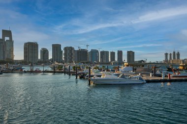 Lusail City 'deki Lusail marinası, Katar yatları ve Katar bayrağı taşıyan tekneleri olan Katar gündüz manzarası, arka planda bulutlar.