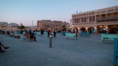 Souq Waqif, Doha, Katar ana caddesinde gün batımında geleneksel Arap Tekstil Dükkanı, Kafeler, yerliler ve yürüyen ziyaretçileri gösteriyor. Katar Corona virüs salgınından sonra yeniden açıldı 