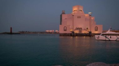 Doha Katar 'daki İslam Sanatları Müzesi. Gün batımı Doha Corniche' den, Arap körfezinde botla ve arka planda ufuk çizgisiyle çekilmiş.