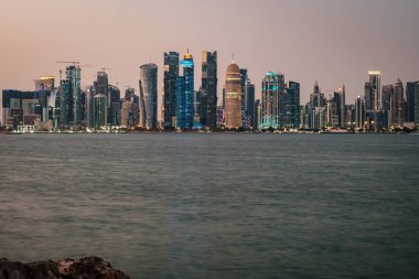 Doha Katar geceleri gökdelenleri gösteren gökdelenler Arap körfezine yansıyor.