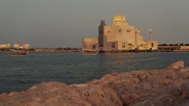 Doha Katar 'daki İslam Sanatları Müzesi. Gün batımı Doha Corniche' den, Arap körfezinde botla ve arka planda ufuk çizgisiyle çekilmiş.