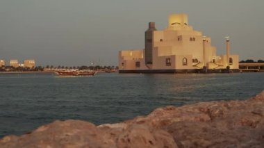 Doha Katar 'daki İslam Sanatları Müzesi. Gün batımı Doha Corniche' den, Arap körfezinde botla ve arka planda ufuk çizgisiyle çekilmiş.