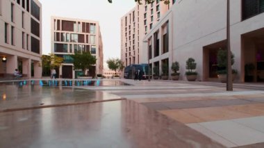 Doha 'daki Msheireb Şehir Merkezi, Katar öğleden sonra, binaların benzersiz mimarisini, yerel halk ve ziyaretçilerin yürüdüğü Modern Tram' ı gösteren bir çekim.