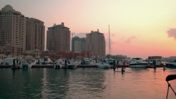 パラル ドーハのポルト アラビア マリーナ ドッキングボートやヨットを示すカタールの日没のショット アラビア湾でのカヤック訓練 背景にある住宅建築物 — ストック動画