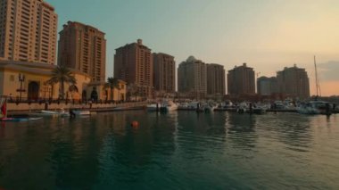 Katar Peral Doha 'daki Porto Arabistan yat limanında öğleden sonra çekilen fotoğrafta arka plandaki rıhtım tekneleri, yatlar ve konut binaları görülüyor.