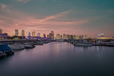 Lusail şehrinde Lusail marinası, günbatımında Katar, yatlar ve tekneler, arka planda Lusail silueti ve bulutları