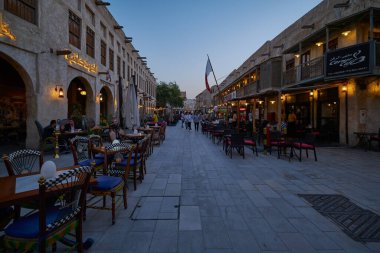 Souq Waqif Doha, Katar gündüz görüşü ana caddeyi kafein, restoranlar, yürüyen insanlar ve Katar bayrağı ile gösteriyor