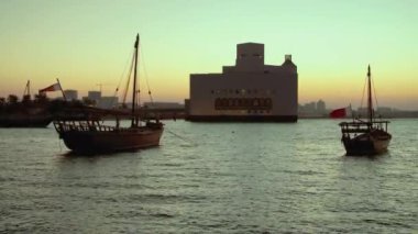 Doha 'daki İslam Sanatları Müzesi, Katar' ın dış batımı, Arap Körfezi 'nde ön planda Katar bayrağı ve arka planda bulutlar ile dalışları gösteren görüntüler.