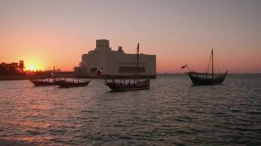 Doha 'daki İslam Sanatları Müzesi, Katar' ın dış batımı, Arap Körfezi 'nde ön planda Katar bayrağı ve arka planda bulutlar ile dalışları gösteren görüntüler.