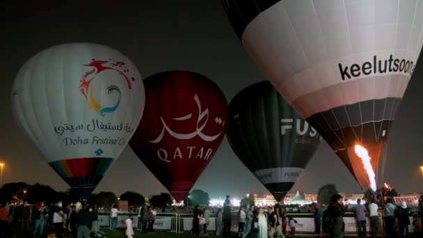 参加者は熱気球を膨らませるために空気を加熱することを示すアピールパークナイトショットでカタール熱気球フェスティバル — ストック動画