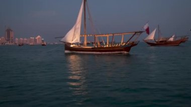 Katara 'nın Doha Katar' daki 11. geleneksel dhow festivali, arka planda Katar bayrağı ve Katara silueti ile gölgeleri gösteren yelkenli tekneden çekildi.
