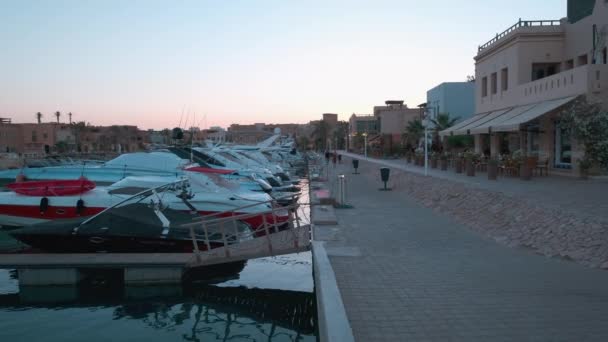 フルガダ 紅海州 エジプトの夕日の景色にアブ ティグ マリーナ観光客の歩行や豪華なヨットを示しています — ストック動画