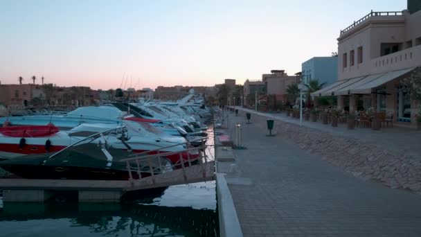 埃及红海省胡尔加达省El Gouna的Abu Tig Marina日落景观 显示游客步行和豪华游艇 — 图库视频影像