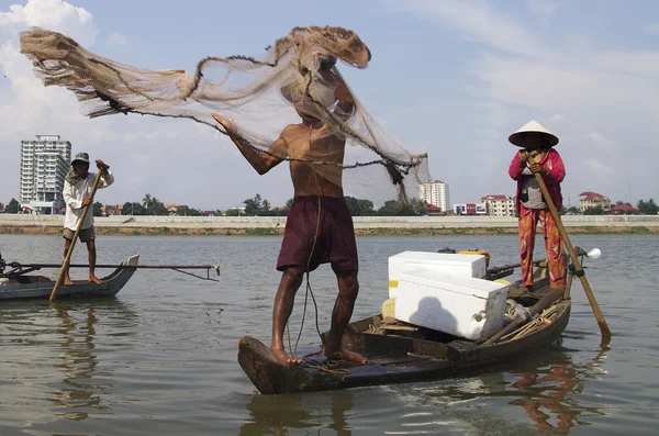 Pescador en una barcaza de madera lanzando una red de pesca en el río — Foto de Stock