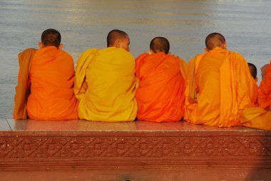 Buddhist monks relaxing at a riverfront clipart