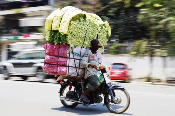 Motociclista con un trasporto di verdure sovraccarico — Foto Stock