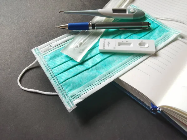 温度計 ノートブック ペンと黒の背景にCovid 19を防ぐための攻撃テストキットを備えた医療用マスク — ストック写真