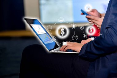 Ofiste sanal simgelerde çevrimiçi iletişimi olan akıllı telefon ve dizüstü bilgisayarla çalışan iş adamı