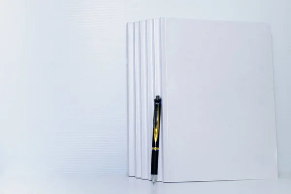 stack of white books and pens on white background isolated in university library