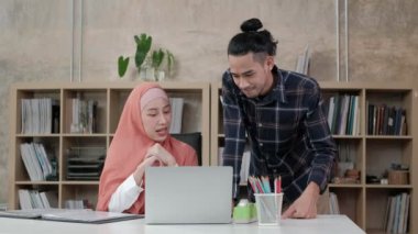 İslamcı olan iki genç girişimci, e-ticaret sektöründe gülümseyerek çalışmanın başarısından bahsediyor. Küçük bir ofiste internet üzerinden çevrimiçi iletişim kurmak için laptop kullan.