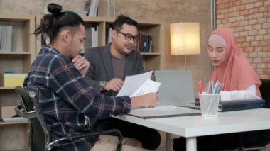 İslami kökenli genç iş arkadaşları, patronlarıyla e-ticaret sektöründe çalışan finansal projeler hakkında konuşuyor. Küçük bir ofiste internet üzerinden çevrimiçi iletişim için dizüstü bilgisayar kullan.
