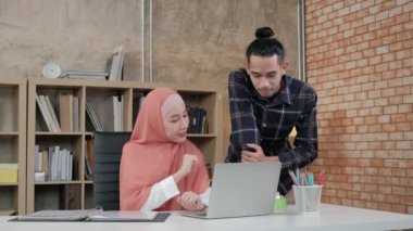 İslamcı olan iki genç girişimci, e-ticaret sektöründe gülümseyerek çalışmanın başarısından bahsediyor. Küçük bir ofiste internet üzerinden çevrimiçi iletişim kurmak için laptop kullan.
