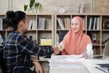 Girişimci iş adamları, İslamcıların ticari ortaklıklarla başa çıkmak için el sıkışıyorlar ve genç bir erkek çalışanın gündelik ofiste bir başarı çizelgesi sunması sonrasında birlikte çalışıyorlar..