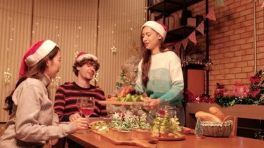 Bir ailenin özel yemeği, genç bir bayan arkadaşlara kızarmış hindi servis eder ve Noel festivali ve yeni yıl kutlaması için dekore edilmiş bir lokantada içkiyle neşelidir..