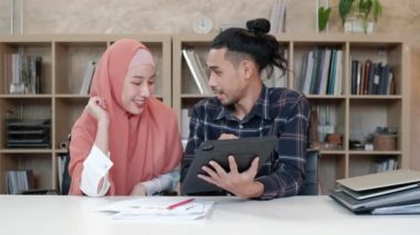 İslamcı çiftler olan iki genç girişimci, e-ticaret sektöründe gülümseyerek çalışmanın başarısı hakkında konuşuyor. Küçük bir ofiste internet üzerinden çevrimiçi iletişim kurmak için laptop kullan.
