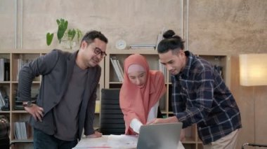 İslami kökenli genç iş arkadaşları, patronlarıyla e-ticaret sektöründe çalışan finansal projeler hakkında konuşuyor. Küçük bir ofiste internet üzerinden çevrimiçi iletişim için dizüstü bilgisayar kullan.
