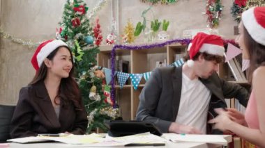 Kırmızı şapkalı üç işçi takımı, iş arkadaşları ve arkadaşları toplanıyor ve şirket tatilinden önce ofiste hediyeler veriyorlar, Noel partisini ve yeni yılı kutlamak için şenlik düzenliyorlar..