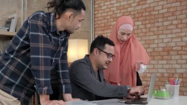 İslami kökenli genç iş arkadaşları, patronlarıyla e-ticaret sektöründe çalışan finansal projeler hakkında konuşuyor. Küçük bir ofiste internet üzerinden çevrimiçi iletişim için dizüstü bilgisayar kullan.
