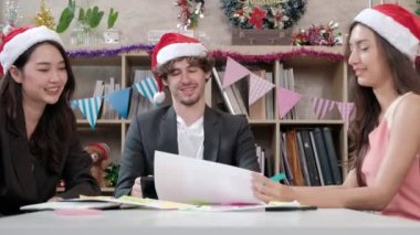 Kırmızı şapkalı, köpekli, arkadaşlarıyla ve iş arkadaşlarıyla üç işçi takımı şirket tatillerinden önce ofiste toplanıp gevşeyecekler, Noel partisini ve yeni yılı kutlamak için şenlik düzenleyecekler..