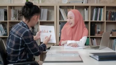 Güzel bir İslami patrona e-ticaret grafikleri ile iş dünyasının başarısı için sunum ve tartışma yapan, küçük bir ofiste masa başı işi yapan bir erkek işçi..