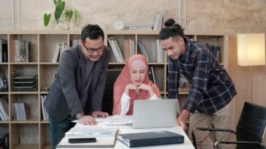 İslami kökenli genç iş arkadaşları, patronlarıyla e-ticaret sektöründe çalışan finansal projeler hakkında konuşuyor. Küçük bir ofiste internet üzerinden çevrimiçi iletişim için dizüstü bilgisayar kullan.
