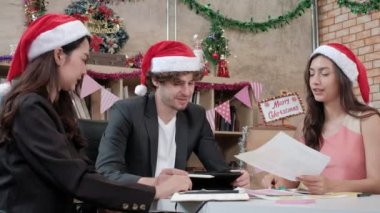 Kırmızı şapkalı, arkadaşları ve iş arkadaşları olan üç işçi takımı şirket tatilinden önce ofiste toplanıp gevşeme, Noel partisini ve yeni yılı kutlamak için festival dekorasyonu yapıyorlar..