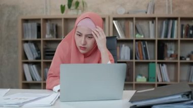 Başörtüsü olan güzel bir Müslüman girişimci kendini yorgun hissediyor ve e-ticaret işi için endişeleniyor. Küçük ofis işyerlerindeki dizüstü bilgisayarlardan internet siparişleri yüzünden kaybediyoruz..
