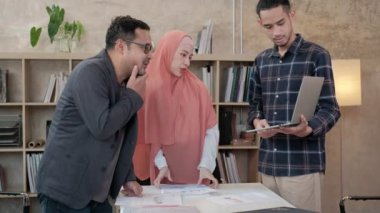 İslami kökenli genç iş arkadaşları, patronlarıyla e-ticaret sektöründe çalışan finansal projeler hakkında konuşuyor. Küçük bir ofiste internet üzerinden çevrimiçi iletişim için dizüstü bilgisayar kullan.