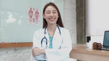 Üniformalı, steteskoplu, gülümseyen ve klinikte kameraya bakan Asya kökenli güzel bir kadın doktor portresi. Profesyonel tedavi konusunda uzman biri..