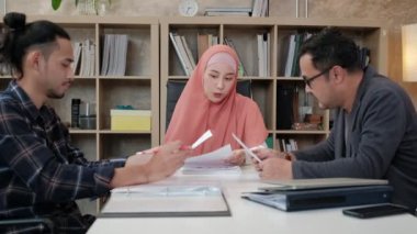Girişimci iş arkadaşları patronlarıyla, güzel Müslüman bir kadınla e-ticaret sektöründe çalışan finansal projeler hakkında konuşuyorlar. Küçük bir ofiste internet üzerinden çevrimiçi iletişim için dizüstü bilgisayar kullan.