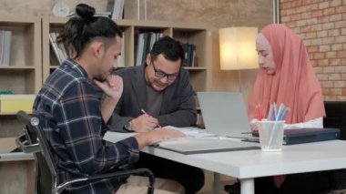 İslami kökenli genç iş arkadaşları, patronlarıyla e-ticaret sektöründe çalışan finansal projeler hakkında konuşuyor. Küçük bir ofiste internet üzerinden çevrimiçi iletişim için dizüstü bilgisayar kullan.