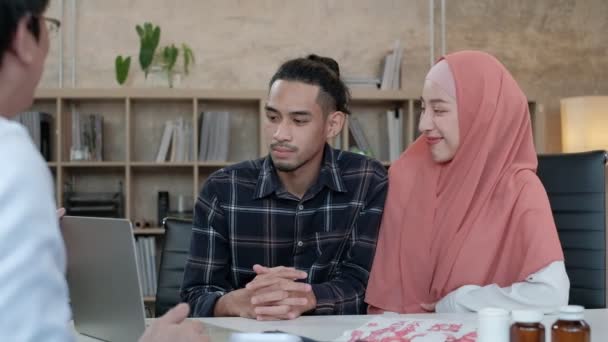 人々医療保険クリニックサービス 若いイスラム教徒のカップルは 美しい女性である彼の妻の健康について プロのアジアの男性医師と話し合い 相談しますオフィスでヒジャーブを身に着けています — ストック動画