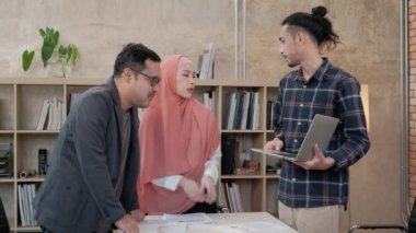 İslami kökenli genç iş arkadaşları, patronlarıyla e-ticaret sektöründe çalışan finansal projeler hakkında konuşuyor. Küçük bir ofiste internet üzerinden çevrimiçi iletişim için dizüstü bilgisayar kullan.