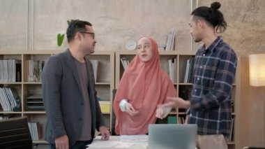 İslami kökenli genç iş arkadaşları, patronlarıyla e-ticaret sektöründe çalışan finansal projeler hakkında konuşuyor. Küçük bir ofiste internet üzerinden çevrimiçi iletişim için dizüstü bilgisayar kullan.