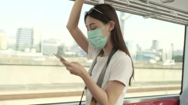 Yüz maskeli ve kameralı Asyalı kadın turist, seyahat haritasını cep telefonuyla arıyor, şehir içi tren ulaşımı, akıllı telefonla şehir hayatı yolculuğu, Tayland 'da mutlu tatiller..