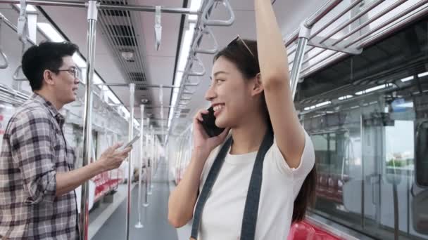空の空の電車の中で2人の若い乗客 携帯電話で話すカメラの観光客と美しいアジアの女性 タイの都市鉄道輸送との旅行 幸せなライフスタイルの旅の休暇 — ストック動画