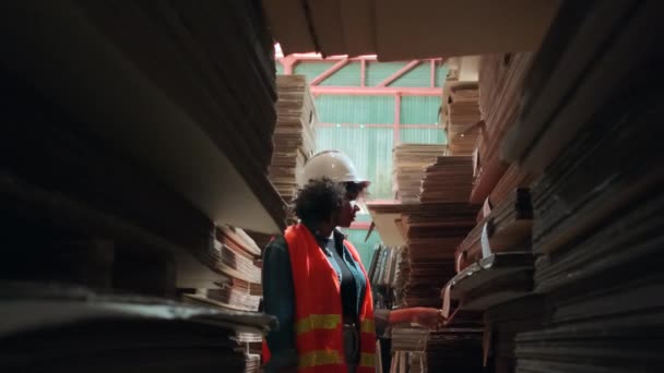 アフリカ系アメリカ人女性労働者の安全統一とハード帽子 工場倉庫でのスーパーバイザー包装在庫注文 積層紙製造の山 リサイクル製造業 — ストック動画