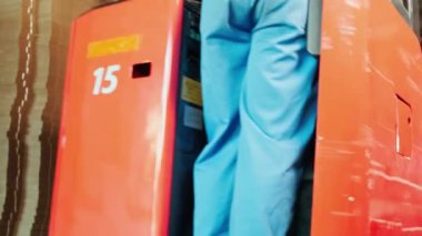 Endüstri fabrikası çalışanları güvenlik üniforması ve hard hat ile depolamayı dizüstü bilgisayarla kontrol ediyorlar depoda stok siparişleri, karton istifleme kartonlarını forklift ile dolduruyorlar, ürün lojistiği üretiyorlar..