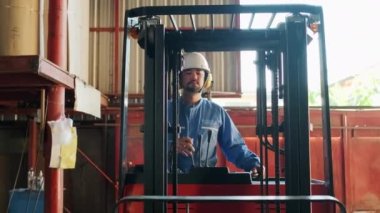 Güvenlik üniformalı Asyalı erkek endüstriyel işçi ve başlık hidrolik forklift kullanıyor, nakliye ve lojistik nakliye ambar imalat fabrikasında, profesyonel sürücü işgali stokları.
